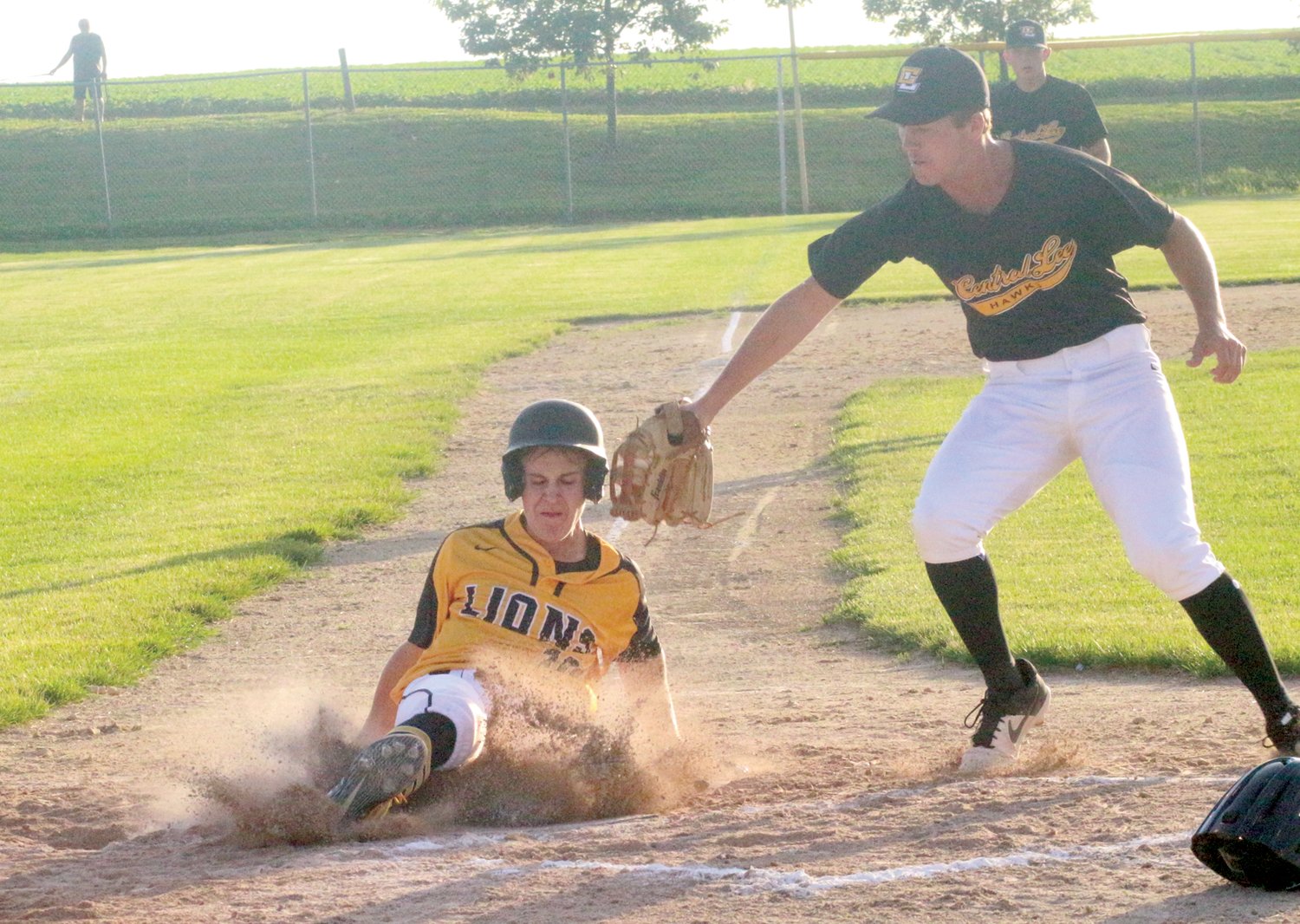 Lone Tree’s Cade Shield slides safely into home plate during their June 24 game against Louisa-Muscatine.